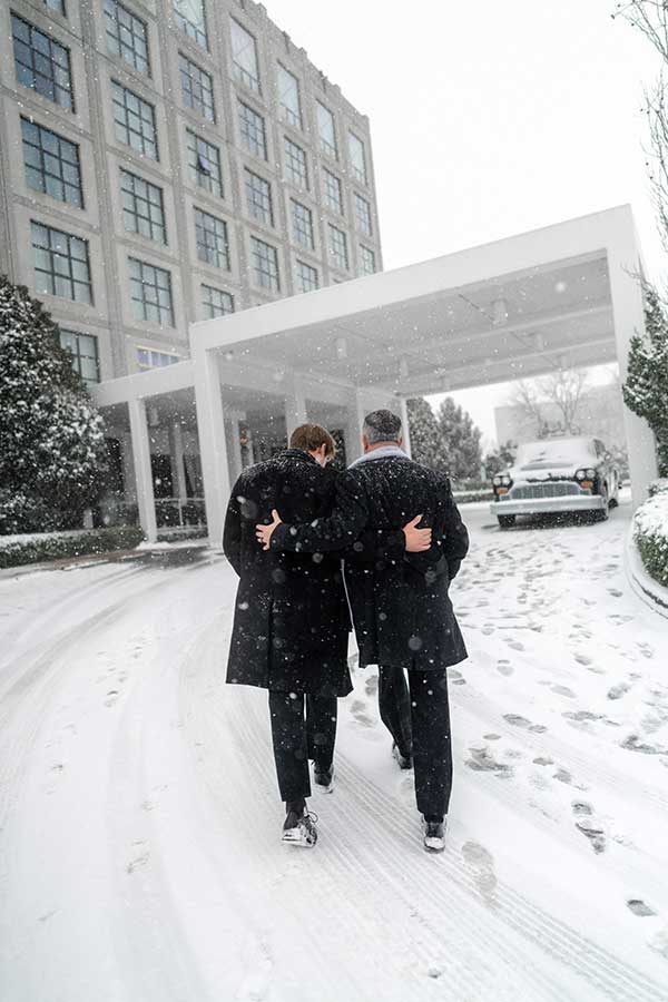 Sam | Photo by Griffin Hart Davis Photography The groom greets and walks through the snow with a guest into the hotel.