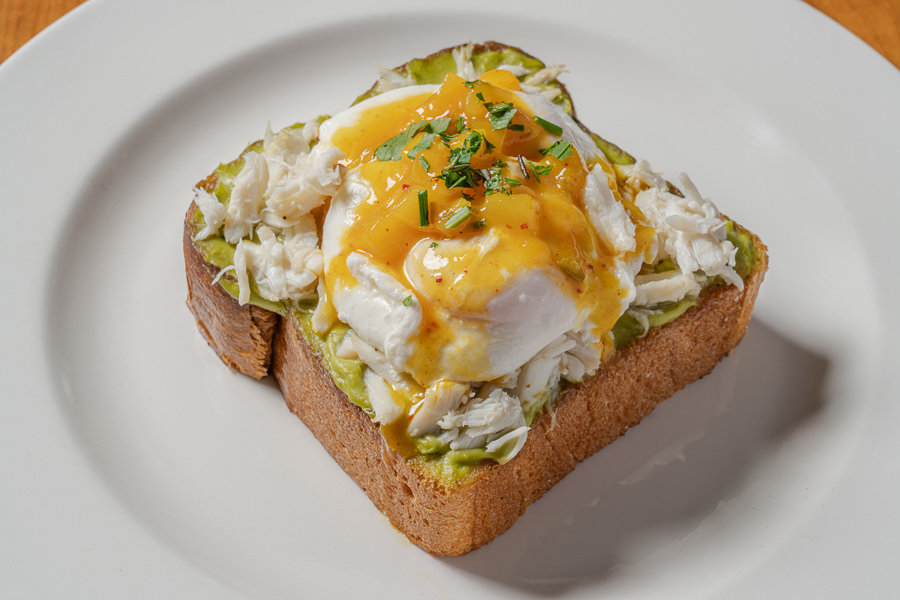 AVOCADO TOAST, challah, avocado mousse, blue crab, mango coulis, poached eggs, Greek yogurt, housemade granola