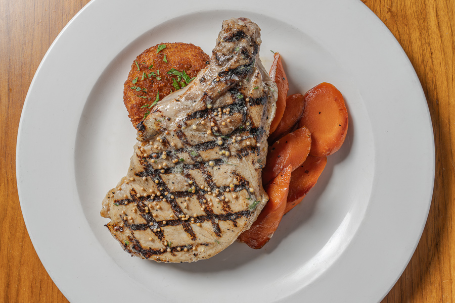 GRILLED PORK CHOP, mustard-tarragon butter, cheddar, bacon & chive potato cake, Vichy carrots